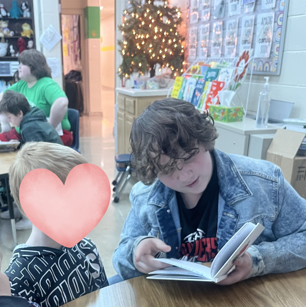 An older student reads to a younger student.