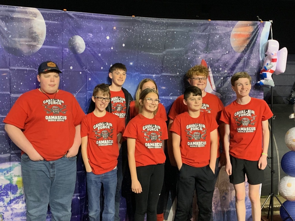 A group of students pose in front of an outer space background.
