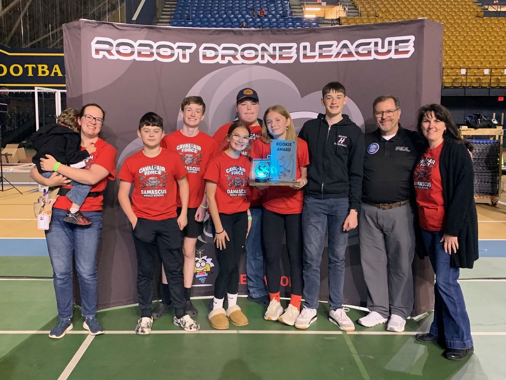 A group of people pose in front of a Robot Drone League background.