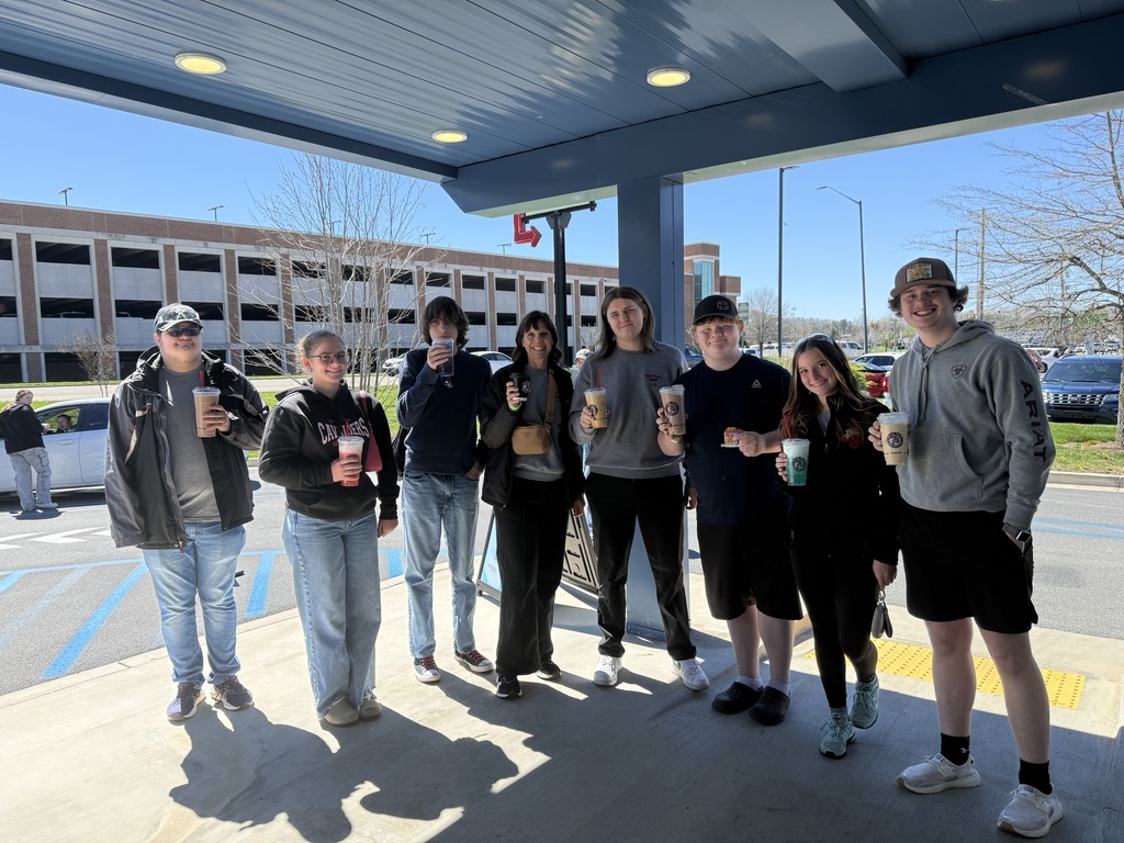 A group of people hold drinks outside a coffee restaurant.