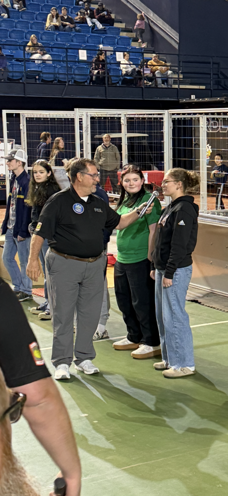 A man interviews a student at a Robotics competition.