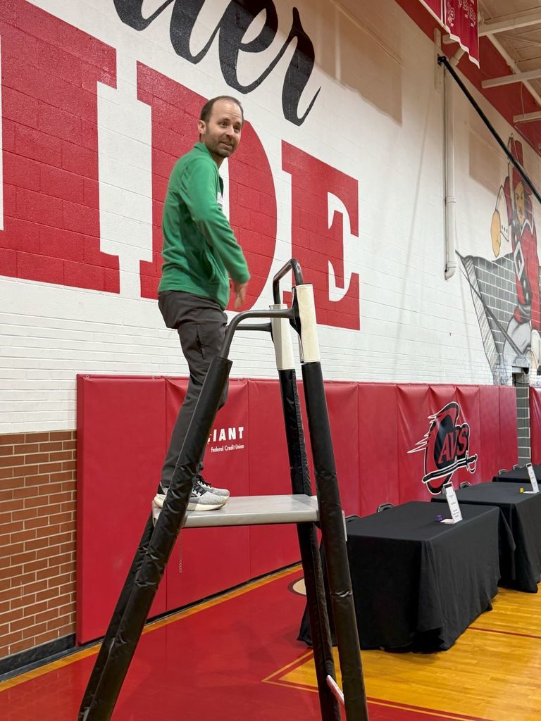 A man stands on a podium in a gym.
