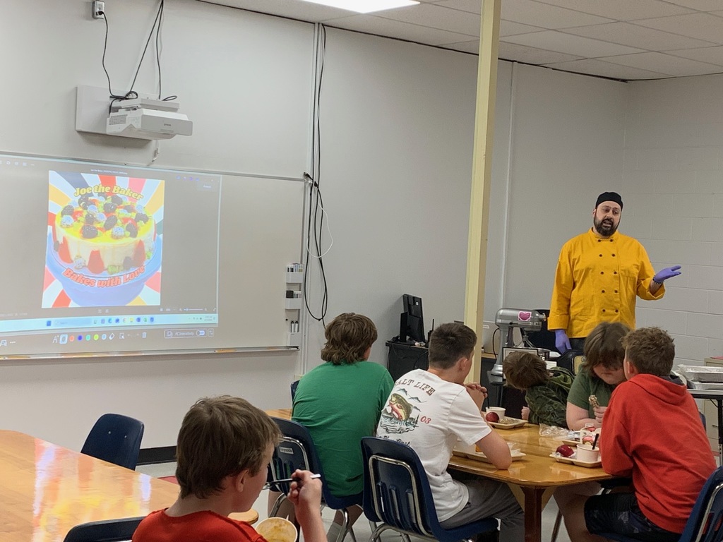 A chef talks to a group of students in a classroom.
