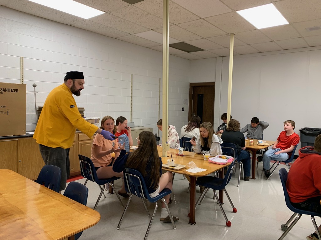 A chef talks to a group of students in a classroom.