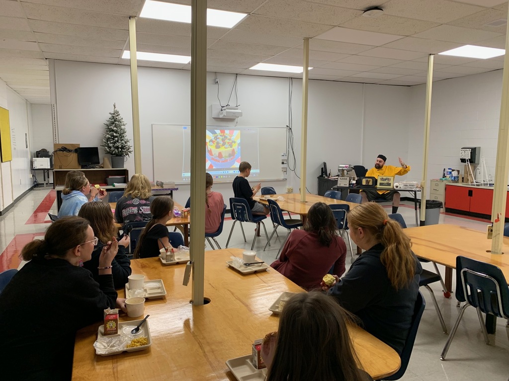 A chef talks to a group of students in a classroom.
