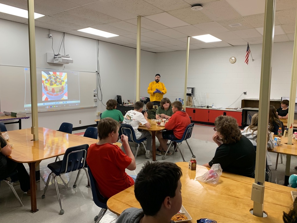 A chef talks to a group of students in a classroom.