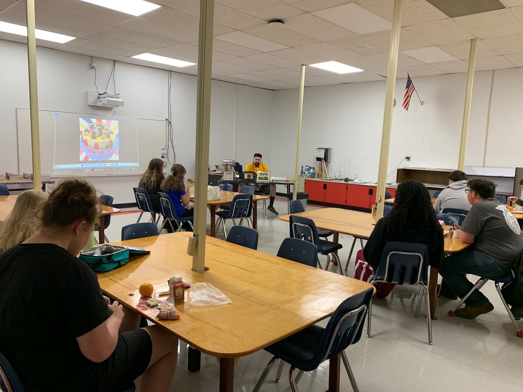 A chef talks to a group of students in a classroom.