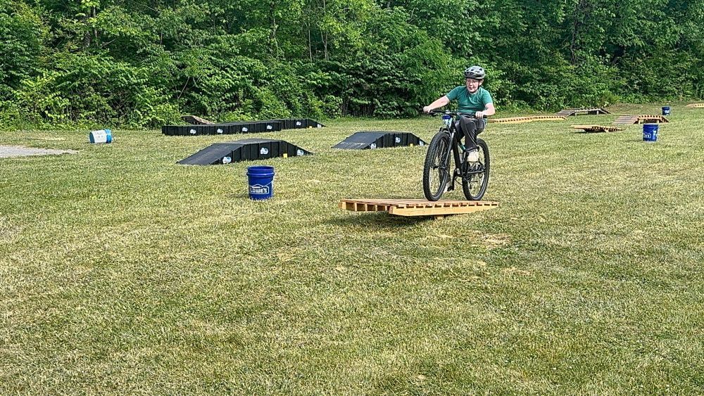 A student rides a bike over a ramp.