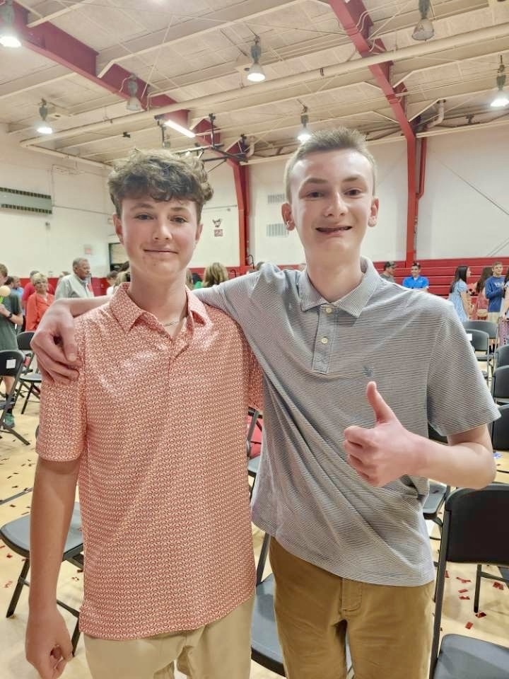 Two boys pose in a gym.