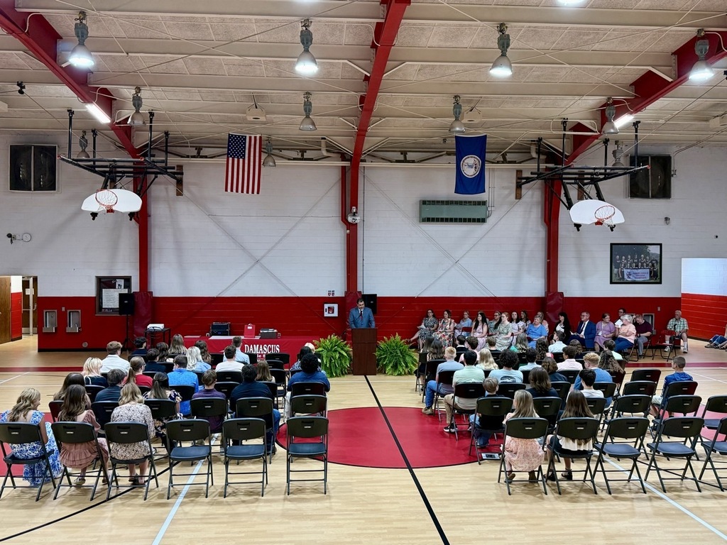A man speaks to students in a gym.