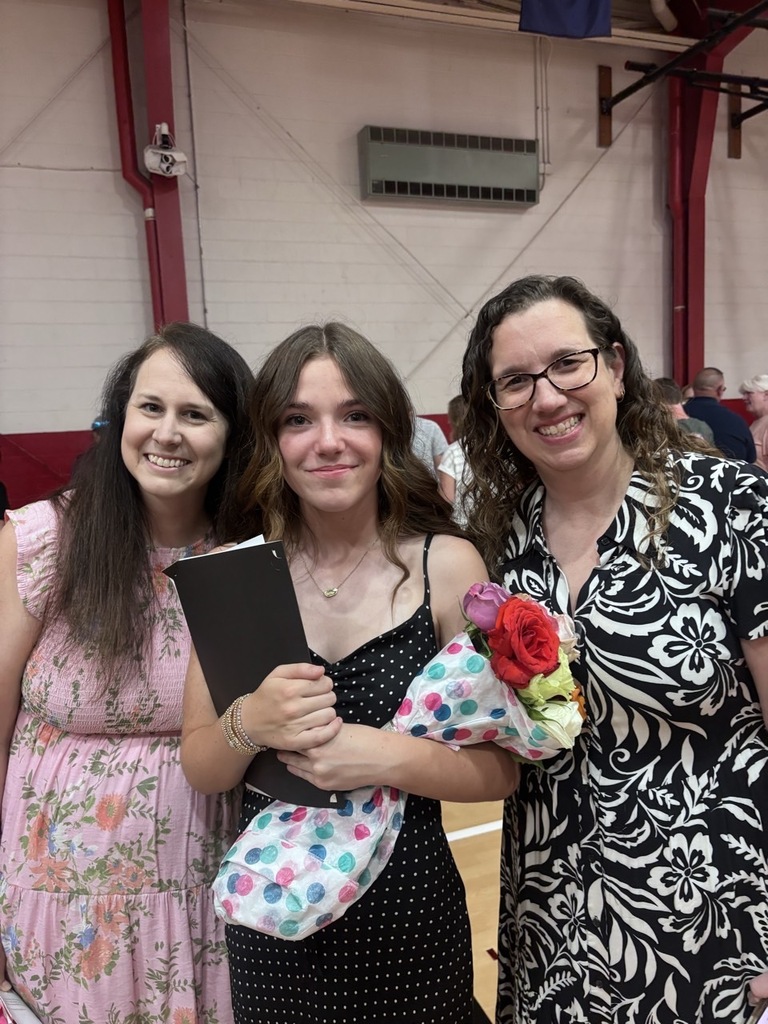 A student stands with two teachers.