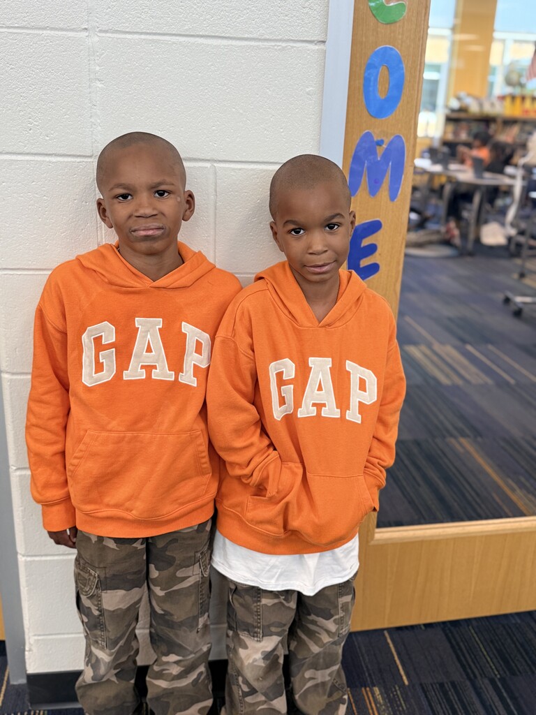 2 students wearing orange GAP sweatshirts and camo pants.