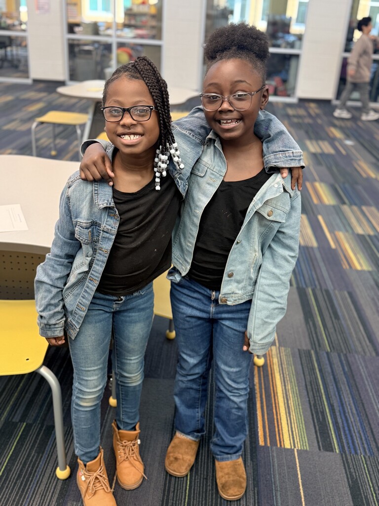 2 girls wearing jeans, black shirts, and jean jackets.