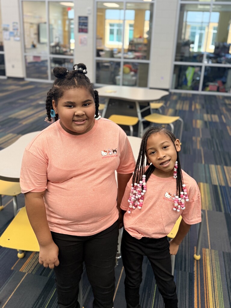 2 twins wearing peach shirts and black pants