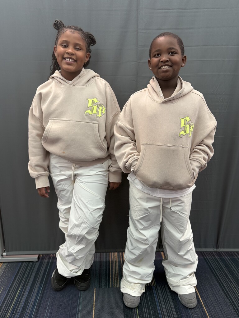 2 students wearing tan jackets and light colored pants.