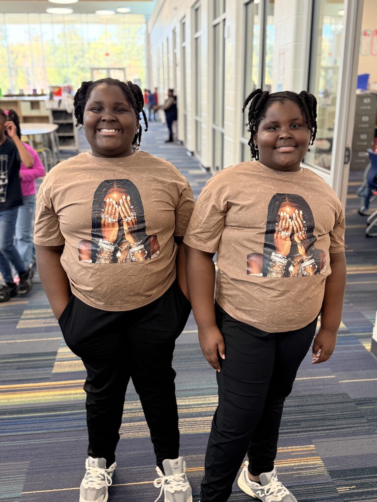 2 twins twinning in brown shirts and black pants.