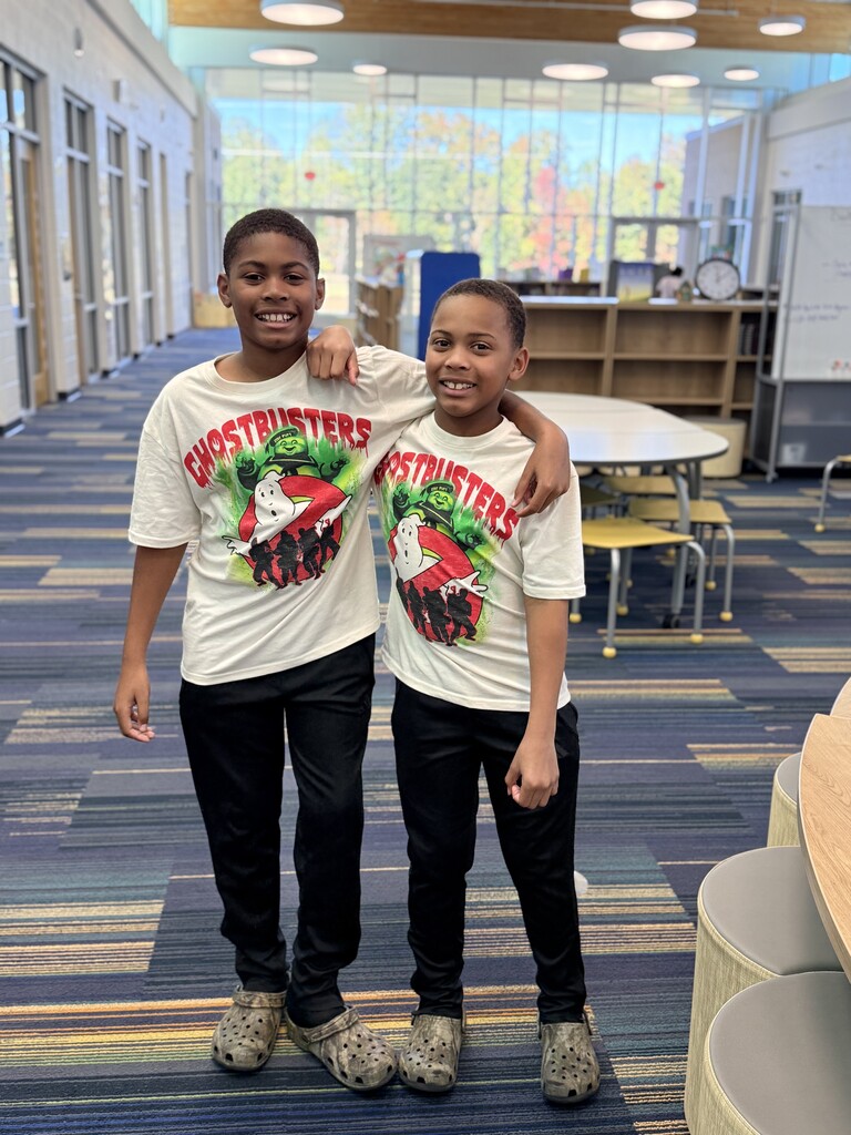 2 students twinning with white Ghostbuster shirts and black pants.