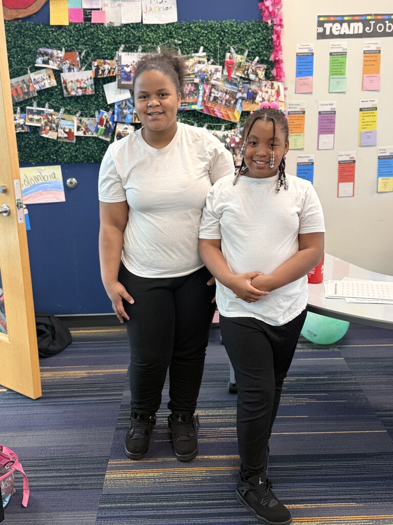 2 students wearing white shirts and black pants.