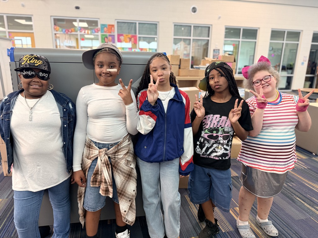 5 fifth grade students with peace signs dressed like it is the 80's and 90's.