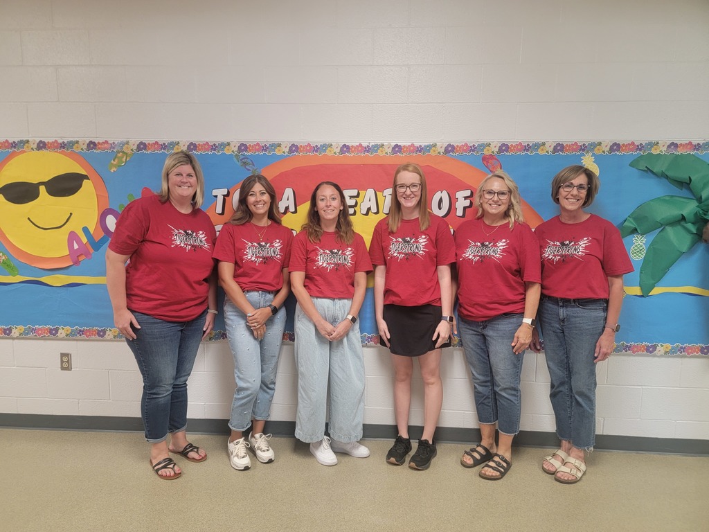 Teachers posing in front of bulletin board.