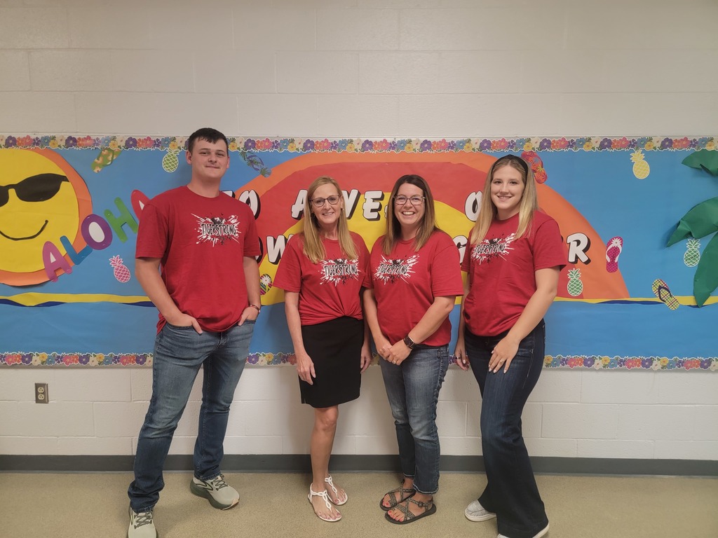 Teachers posing in front of bulletin board.