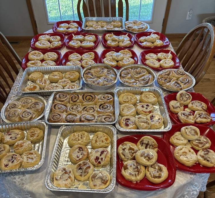 table filled with plates of kolaches and cinnamon rolls