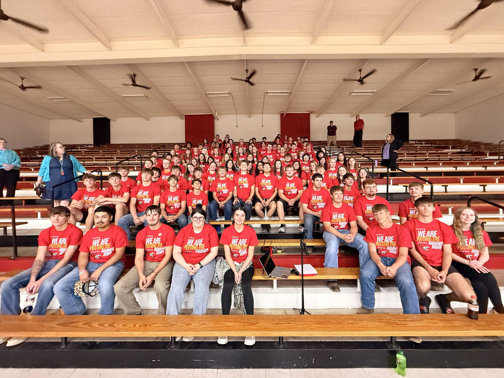 Picture of 9-12 grade students in high school gym before the speaker. Students are wearing their new shirts.