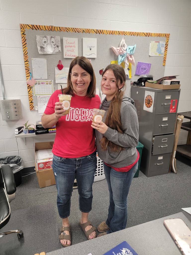 two staff members holding coffee