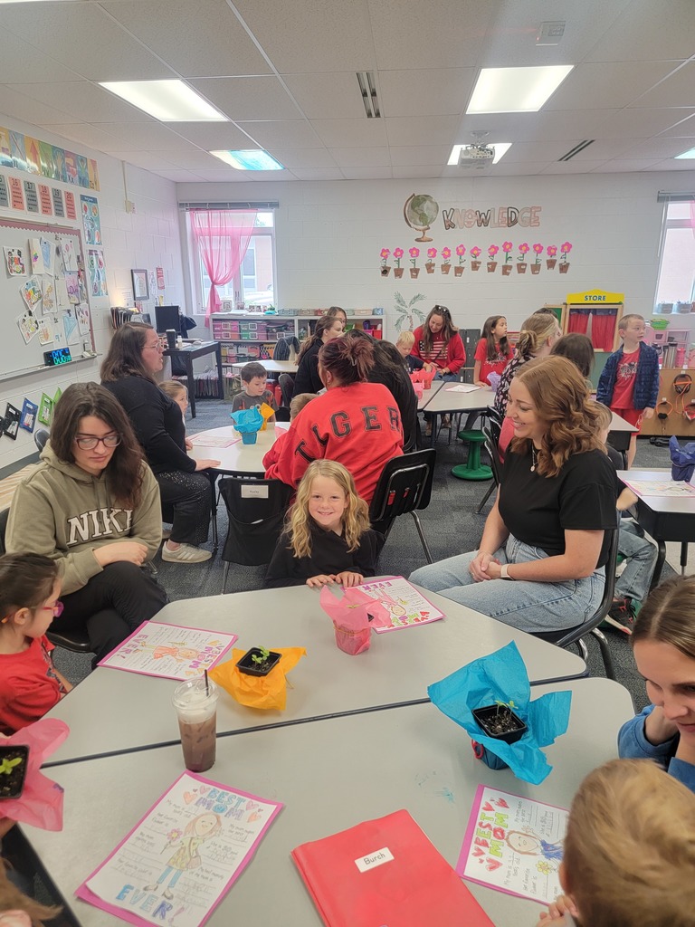 Kindegarten students and moms looking at a drawing.