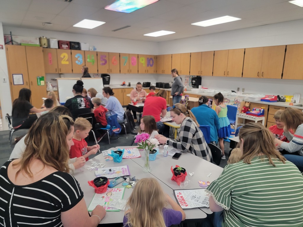Kindegarten students and moms looking at a drawing.