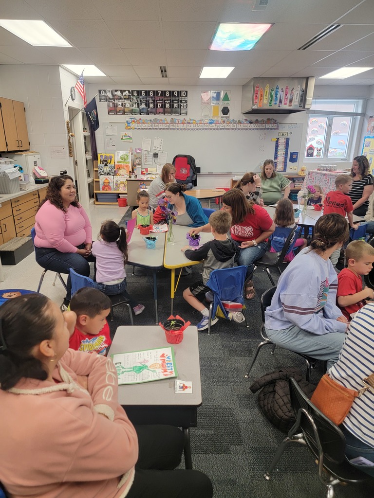 Kindegarten students and moms looking at a drawing.