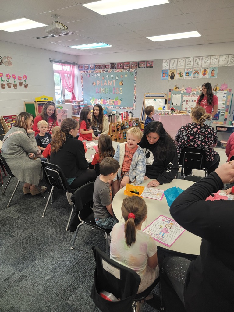 Kindegarten students and moms looking at a drawing.