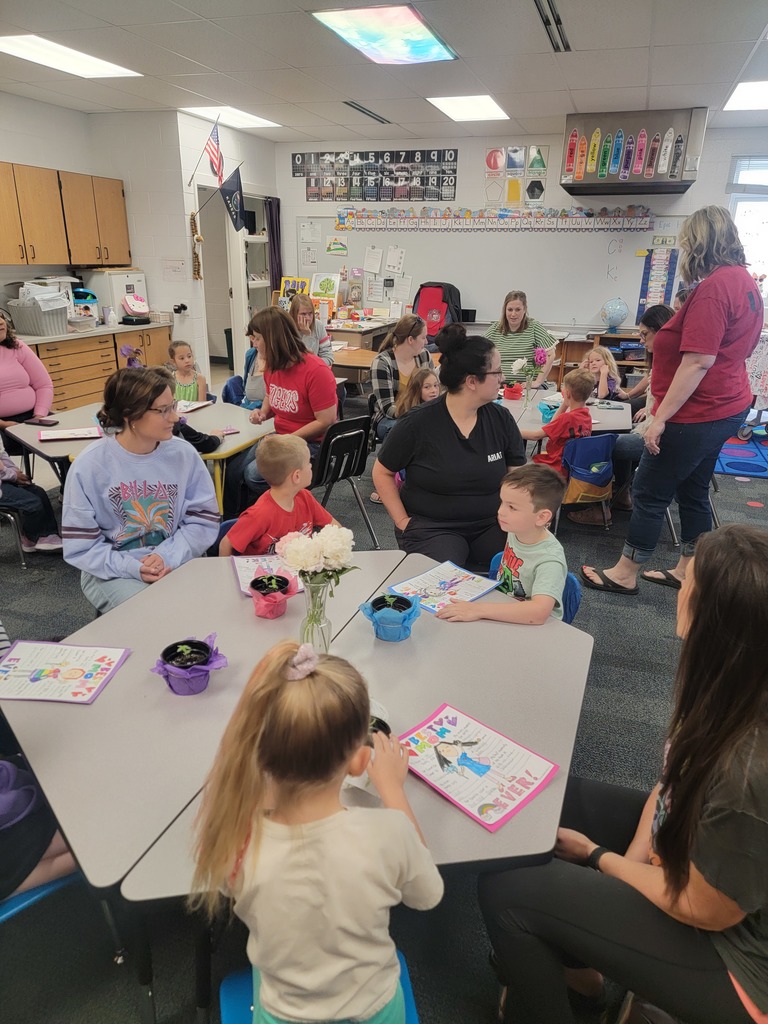 Kindegarten students and moms looking at a drawing.
