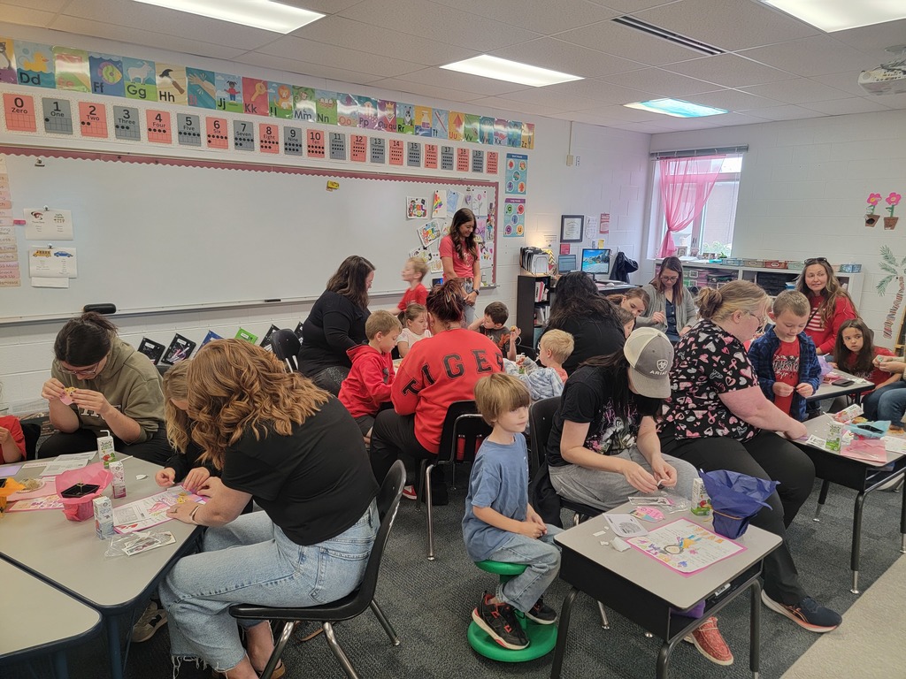 Kindegarten students and moms doing a craft.