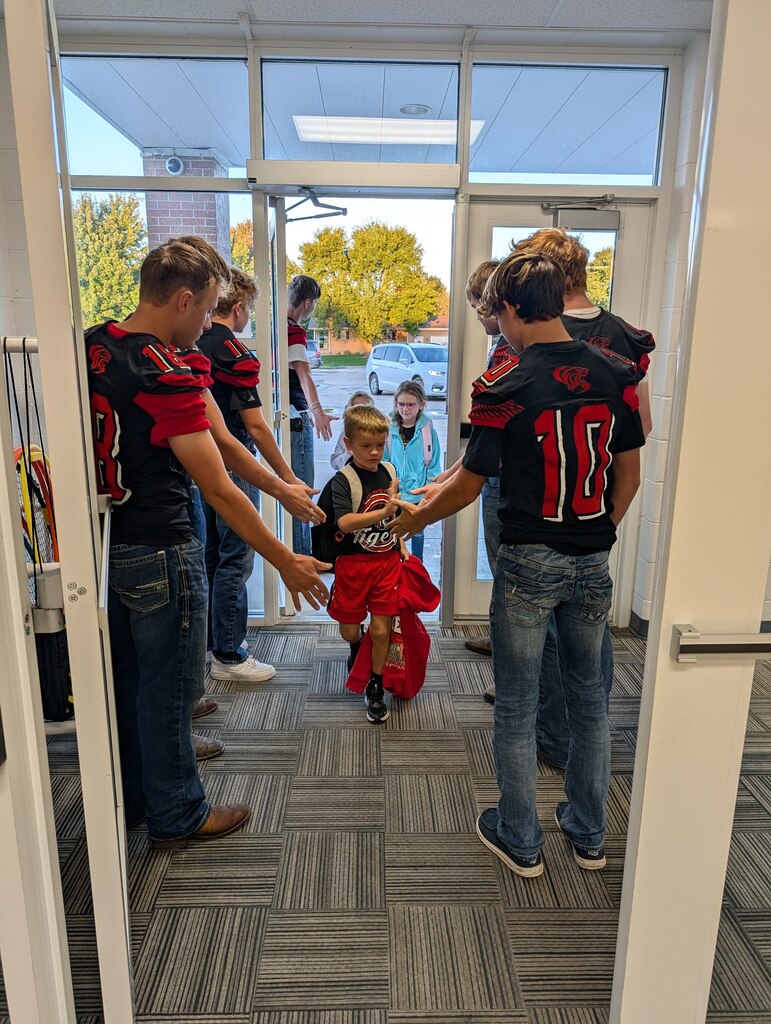 football players greeting students at the front doors