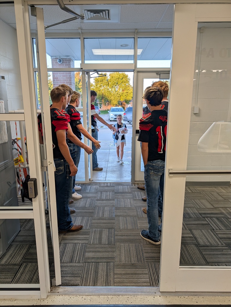 football players greeting students at the front doors