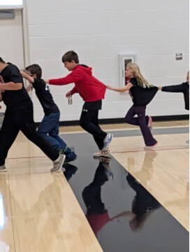 students playing a teamwork game involving running with a hula hoop and holding on to each other