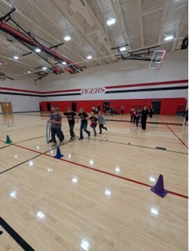 students playing a teamwork game involving running with a hula hoop and holding on to each other