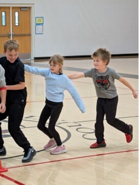 students playing a teamwork game involving running with a hula hoop and holding on to each other