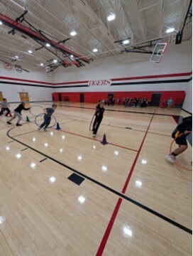 students playing a teamwork game involving running with a hula hoop and holding on to each other