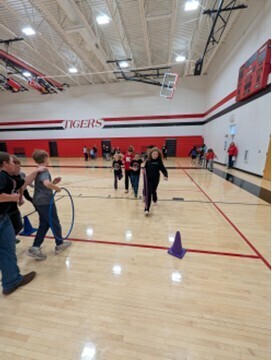 students playing a teamwork game involving running with a hula hoop and holding on to each other