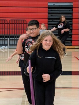 students playing a teamwork game involving running with a hula hoop and holding on to each other