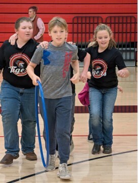 students playing a teamwork game involving running with a hula hoop and holding on to each other
