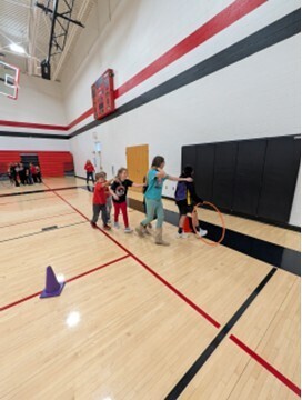 students playing a teamwork game involving running with a hula hoop and holding on to each other