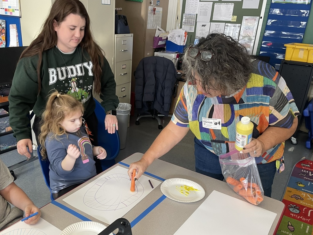 ms sattler helps girl paint with carrot