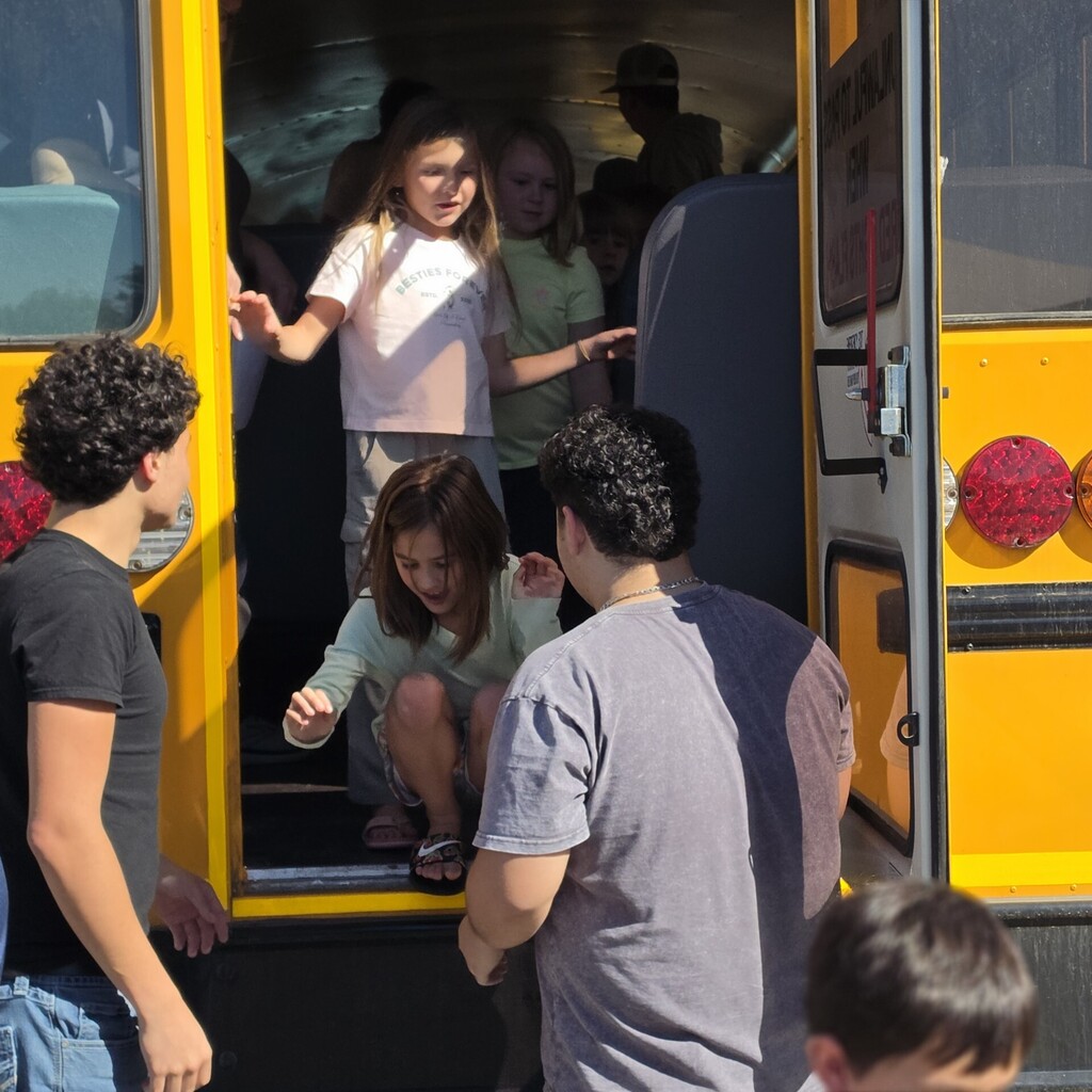 Students helping younger kids get off the bus.