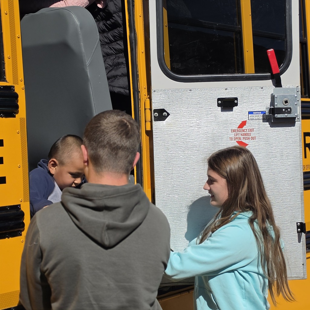 Students helping younger kids off the bus.