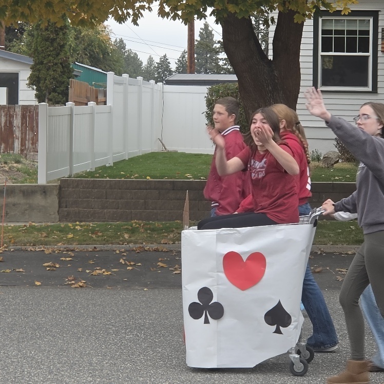 Students riding in a decorated shopping cart.
