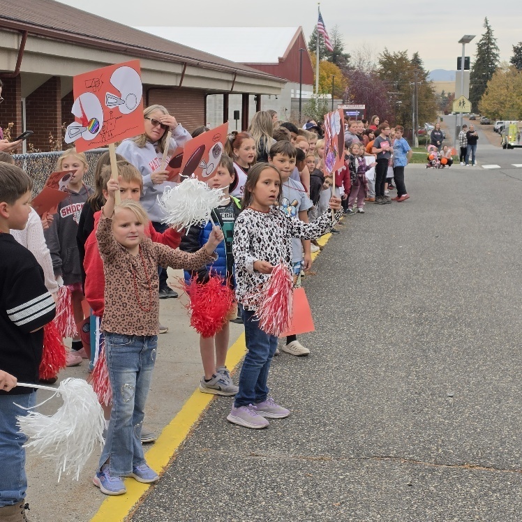 Students in line holding signs and pom poms