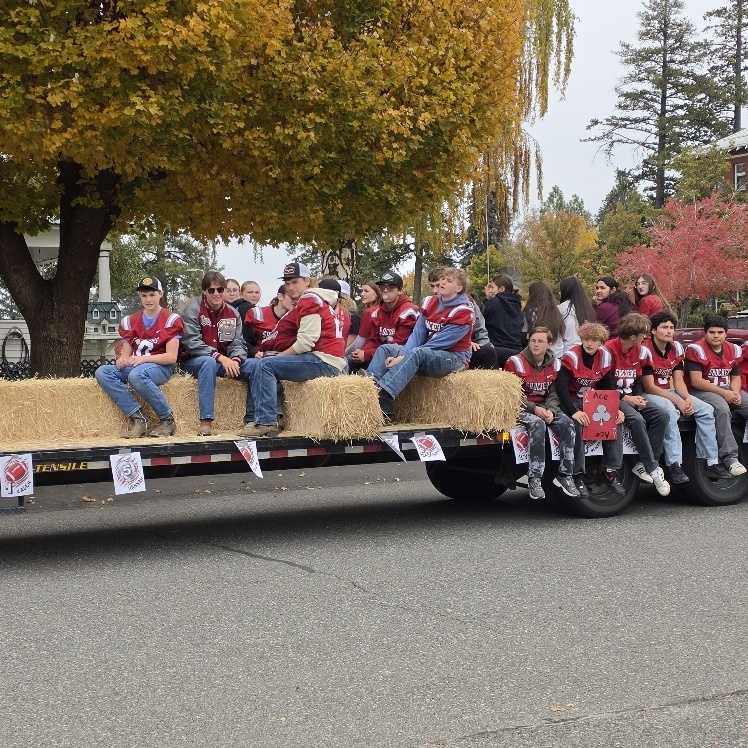 Football players sitting on a trailer during a parade.